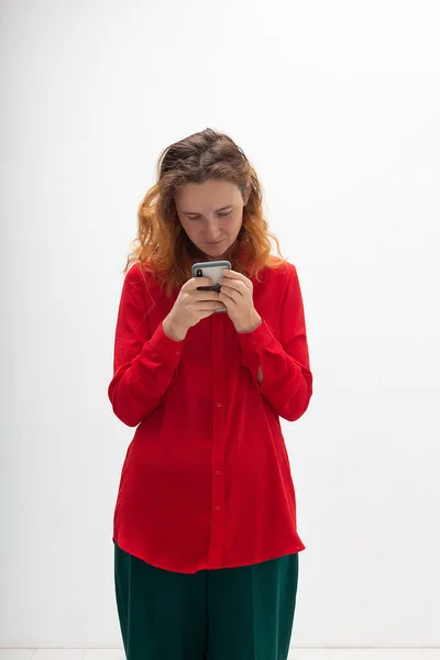 Genç, konsantre olmuş, kızıl saçlı, cep telefonu kullanan, internette sohbet eden bir kadın. — Stok fotoğraf