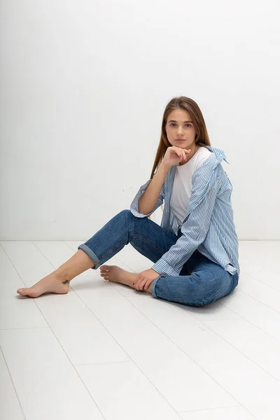 Jeune caucasien jolie fille avec les cheveux longs en chemise, jeans bleu se trouve au studio — Photo