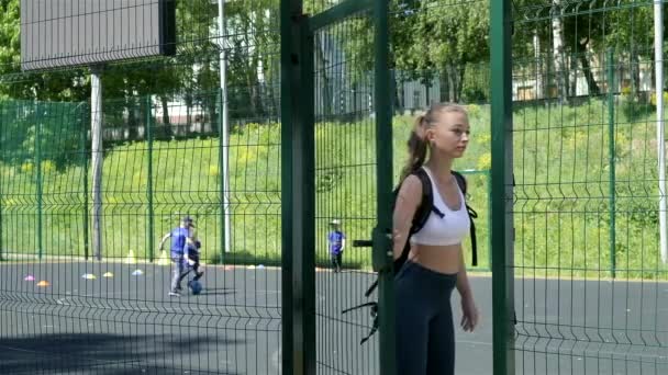 Jeune ajustement sportif blond jolie fille en vêtements de sport ouvre la porte au terrain de sport — Video