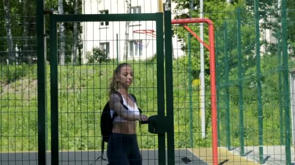 Młody fit atletyczny blondynka ładna dziewczyna w sportowy odzież otwiera drzwi na boisku sportowym — Wideo stockowe