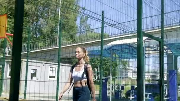 Jovem mulher loira atlética com rabo de cavalo em sportswear andando em campo de esportes — Vídeo de Stock