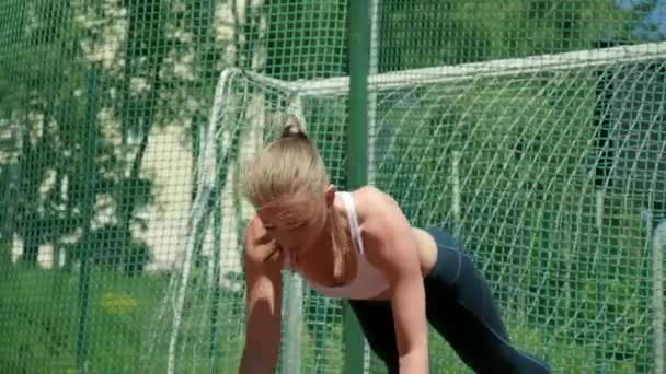 Joven atlética mujer caucásica en ropa deportiva haciendo flexiones con mancuernas — Vídeo de stock