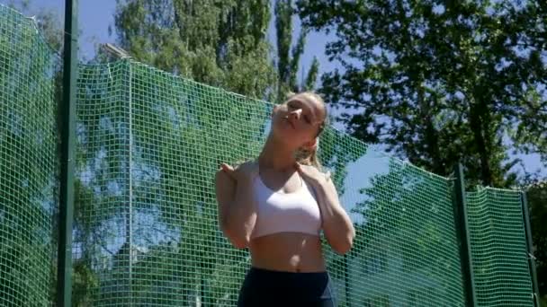 Mladý fit blond busty žena ve sportovním oblečení strečink její krk na sportovišti — Stock video