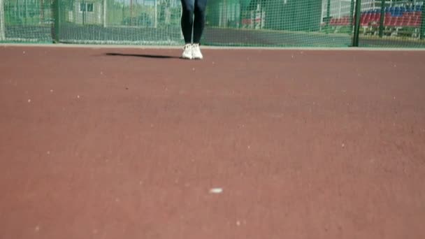 스포츠 맹세를 하는 젊은 여자는 줄을 줄넘기로 스포츠 경기장에서 점프를 한다 — 비디오