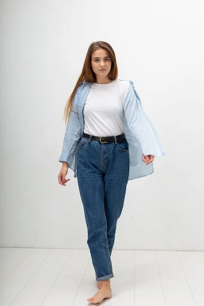 Jovem caucasiano menina bonita com cabelos longos na camisa, jeans azul posa no estúdio — Fotografia de Stock