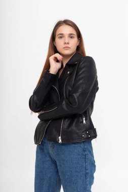 Beyaz arka planda uzun kahverengi saçlı, deri ceketli beyaz bir kadın.