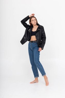 Beyaz arka planda uzun kahverengi saçlı, deri ceketli beyaz bir kadın.