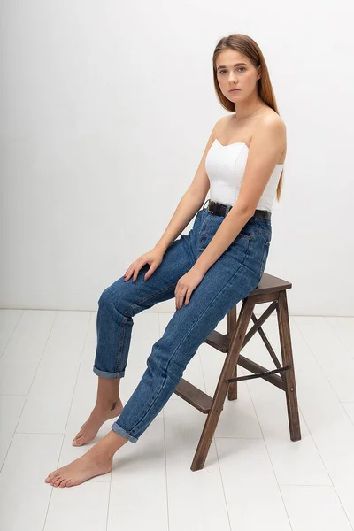 Young caucasian woman with long brown hair in in corset, blue jeans at studio — Stock Photo, Image