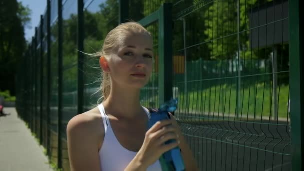 Vonzó kaukázusi nő sportruházatban sportpályán ivóvíz — Stock videók