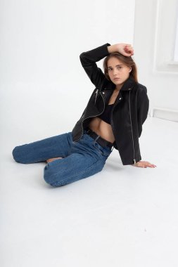 Beyaz arka planda uzun kahverengi saçlı, deri ceketli beyaz bir kadın.