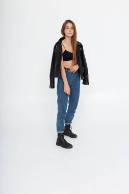 Beyaz arka planda uzun kahverengi saçlı, deri ceketli beyaz bir kadın.