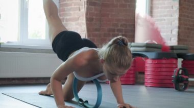 Beyaz tenli güzel bir kadın spor salonunda pilates ringiyle egzersiz yapıyor.