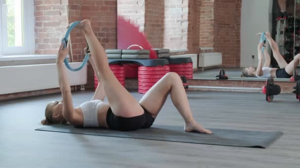 Joven caucásico ajuste deportivo mujer estiramiento piernas con pilates anillo en el gimnasio — Vídeos de Stock