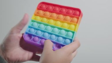 Çocuk oynuyor, gökkuşağı poppit oyuncağında parmakları olan baloncuklar itiyor.