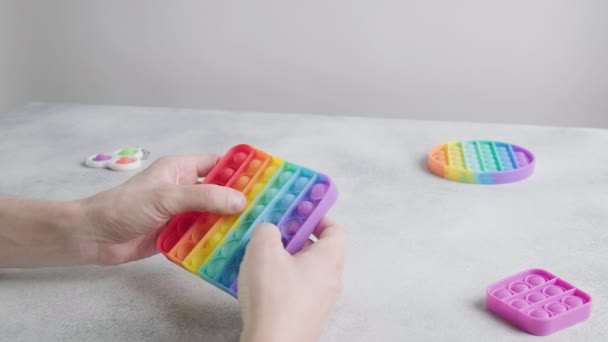 Man spelen, duwen bubbels op trendy regenboog poppit fidget speelgoed met vingers — Stockvideo