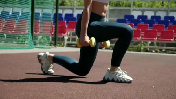 Joven en forma chica deportiva no se abalanza ejercicio en cuclillas con pesas en el campo de deportes — Vídeos de Stock