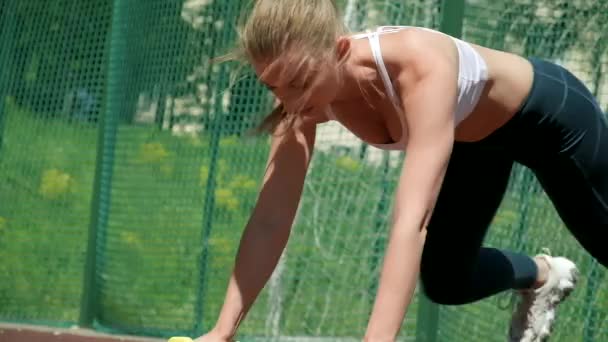 Spor kıyafetli genç beyaz kadın dambıllarıyla şınav çekiyor. — Stok video