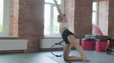 Beyaz tenli güzel bir kadın spor salonunda pilates ringiyle egzersiz yapıyor.