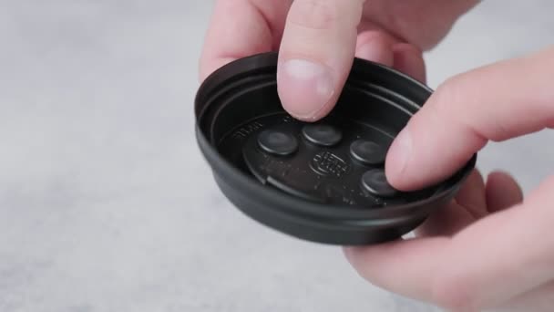 Kind duwt poppit bellen op zwarte plastic dop van koffiebeker met vingers — Stockvideo