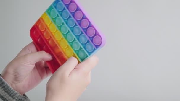 Kind spelen, duwen bubbels op trendy regenboog poppit fidget speelgoed met vingers — Stockvideo