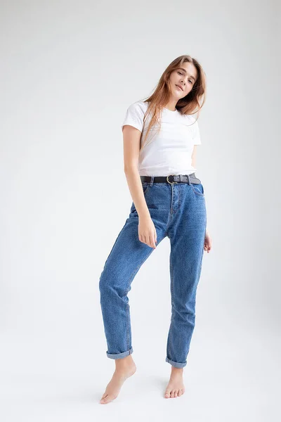 Ung kaukasiska söt flicka med långt hår i t-shirt, blå jeans på studio — Stockfoto