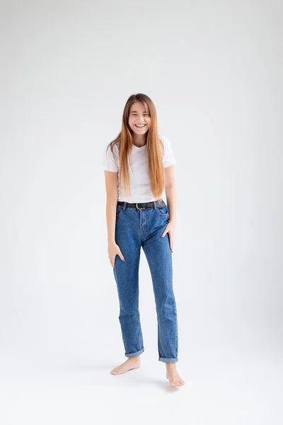 Jong Kaukasisch mooi meisje met lang haar in t-shirt, blauwe jeans in studio — Stockfoto