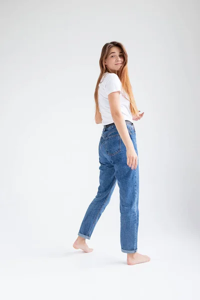 Jovem caucasiano menina bonita com cabelos longos em t-shirt, jeans azuis no estúdio — Fotografia de Stock