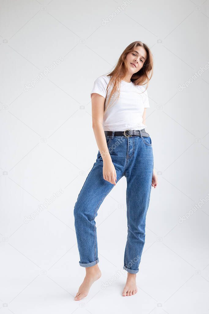 young caucasian pretty girl with long hair in t-shirt, blue jeans at studio