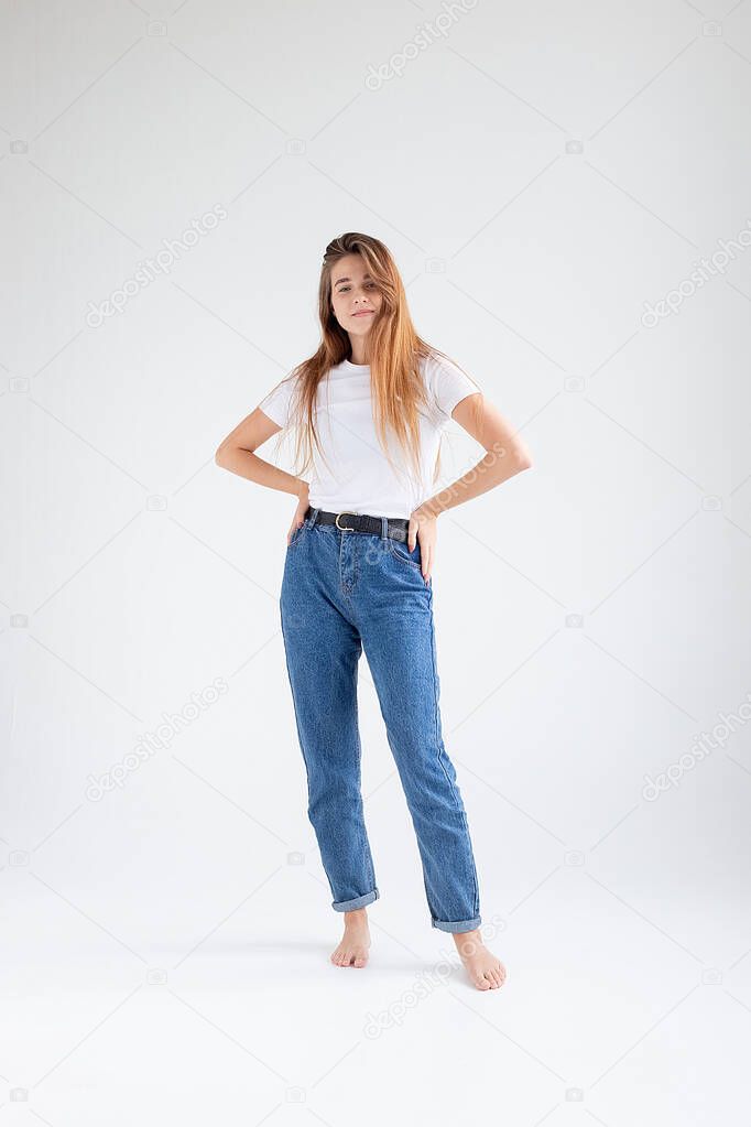 young caucasian pretty girl with long hair in t-shirt, blue jeans at studio