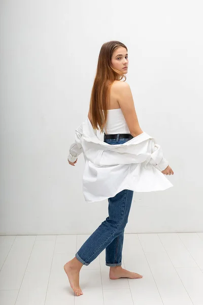 Jonge aantrekkelijke Kaukasische vrouw met lang bruin haar in shirt, blauwe jeans — Stockfoto