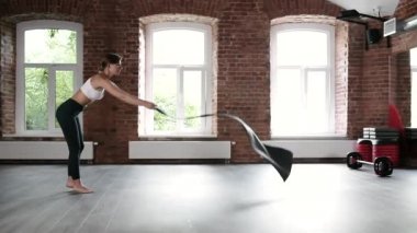 Spor kıyafetli beyaz bir kadın spor salonunda yerde yoga minderi açıyor.