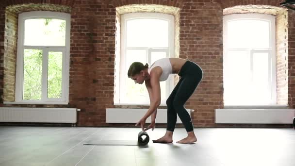 Młoda szczupła biała kobieta w odzieży sportowej zwijająca się na podłodze na siłowni — Wideo stockowe
