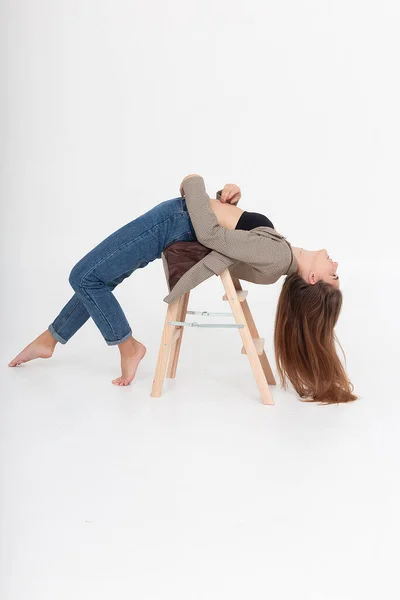 Mager kvinna liggande i broställning på trästege vid ateljé med bara fötter — Stockfoto
