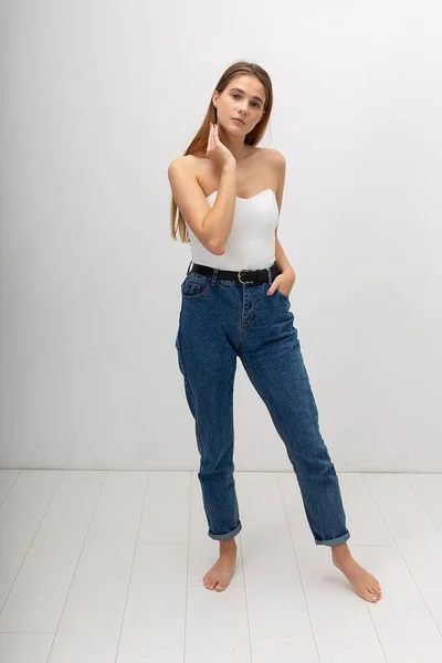 Young attractive caucasian woman with long brown hair in corset, blue jeans — Stock Photo, Image
