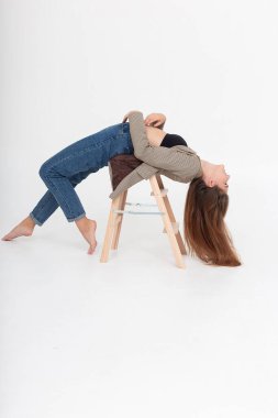 Stüdyoda tahta merdivende çıplak ayakla köprü pozisyonunda uzanan sıska bir kadın.