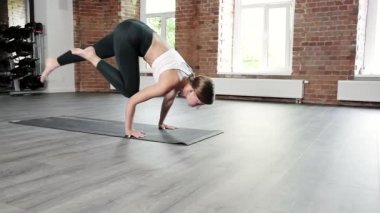 Spor kıyafetli genç beyaz kadın spor salonunda paspasın üstünde duruyor.