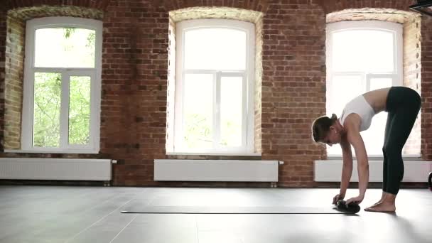 Spor kıyafetli beyaz bir kadın spor salonunda yoga minderini yere yuvarlıyor. — Stok video