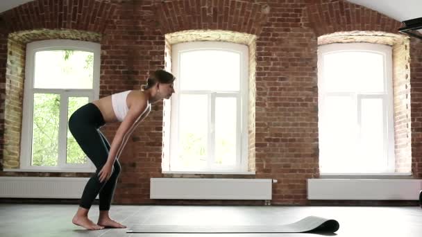 Jong slank Kaukasische vrouw in sportkleding ontrollen yoga mat op vloer in sportschool — Stockvideo