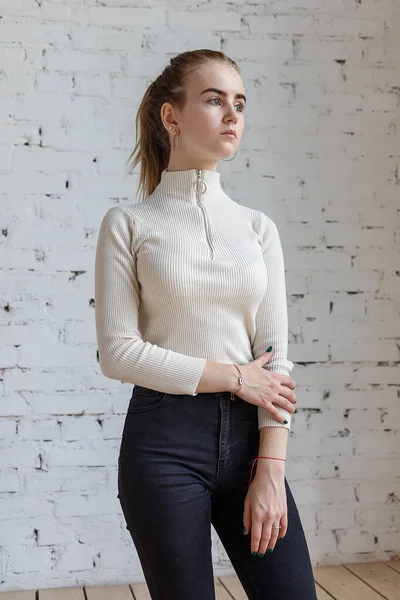 Портрет молодой вдумчивой модели подростка в белом свитере и черных джинсах — стоковое фото
