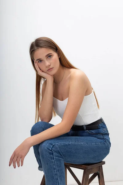 Ung kaukasisk kvinna med långt brunt hår i korsett, blå jeans i studio — Stockfoto