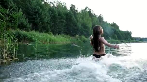 Sexy young girl in bikini jumps into lake to swim, with water splashes around — Vídeo de stock