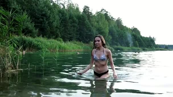Ajuste delgado mojado bonita hembra en bikini caminando fuera del agua después de nadar en el lago — Vídeos de Stock