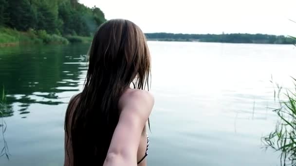 Seductive young fit girl in bikini slowly enters lake to swim holding mans hand — Vídeos de Stock