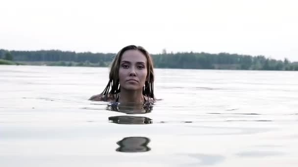 Head of seductive young thin woman swimming in lake above water of pond — Vídeos de Stock
