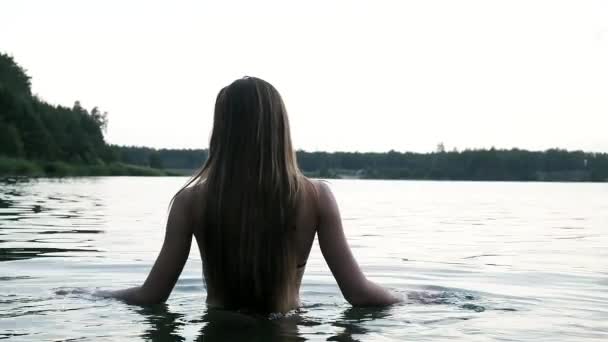Sexy seductora joven esbelta mujer en un bikini negro entra lentamente en el lago para nadar — Vídeos de Stock