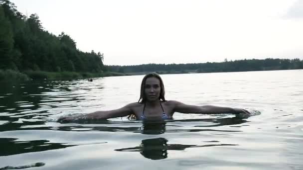 Fit slank nat mooi vrouw in bikini lopen uit het water na het zwemmen in meer — Stockvideo