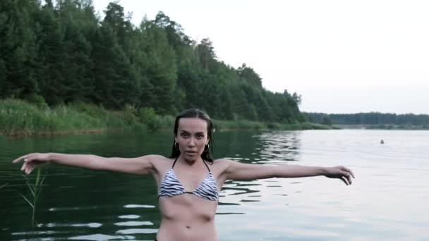 Σέξι νεαρή λεπτή γυναίκα με μπικίνι στέκεται στη λίμνη, πέφτοντας πίσω στο νερό — Αρχείο Βίντεο