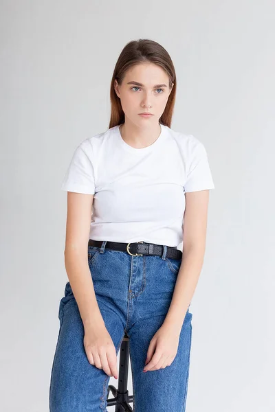 Ung kaukasiska söt flicka med långt hår i t-shirt, blå jeans på studio — Stockfoto