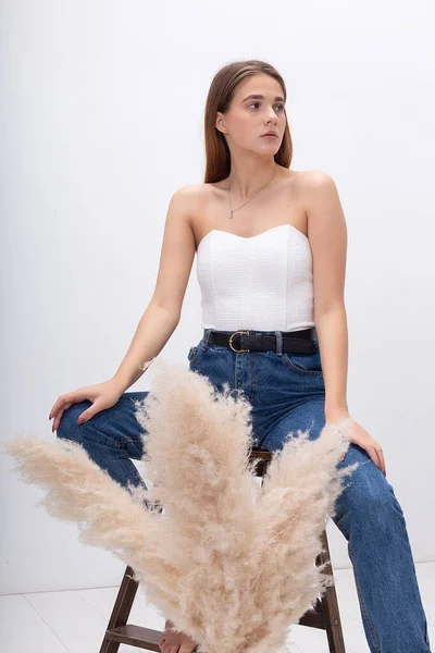 Stüdyoda bir buket otla poz veren uzun saçlı genç ve güzel bir kız.