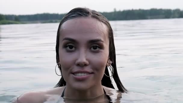 Крупный план на голове молодой привлекательной расслабленной азиатской женщины, плавающей в пруду — стоковое видео